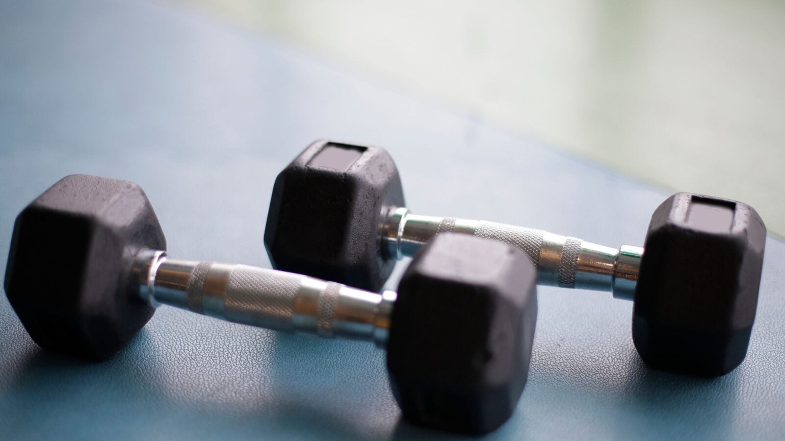 A pair of hex dumbbells on a blue floor