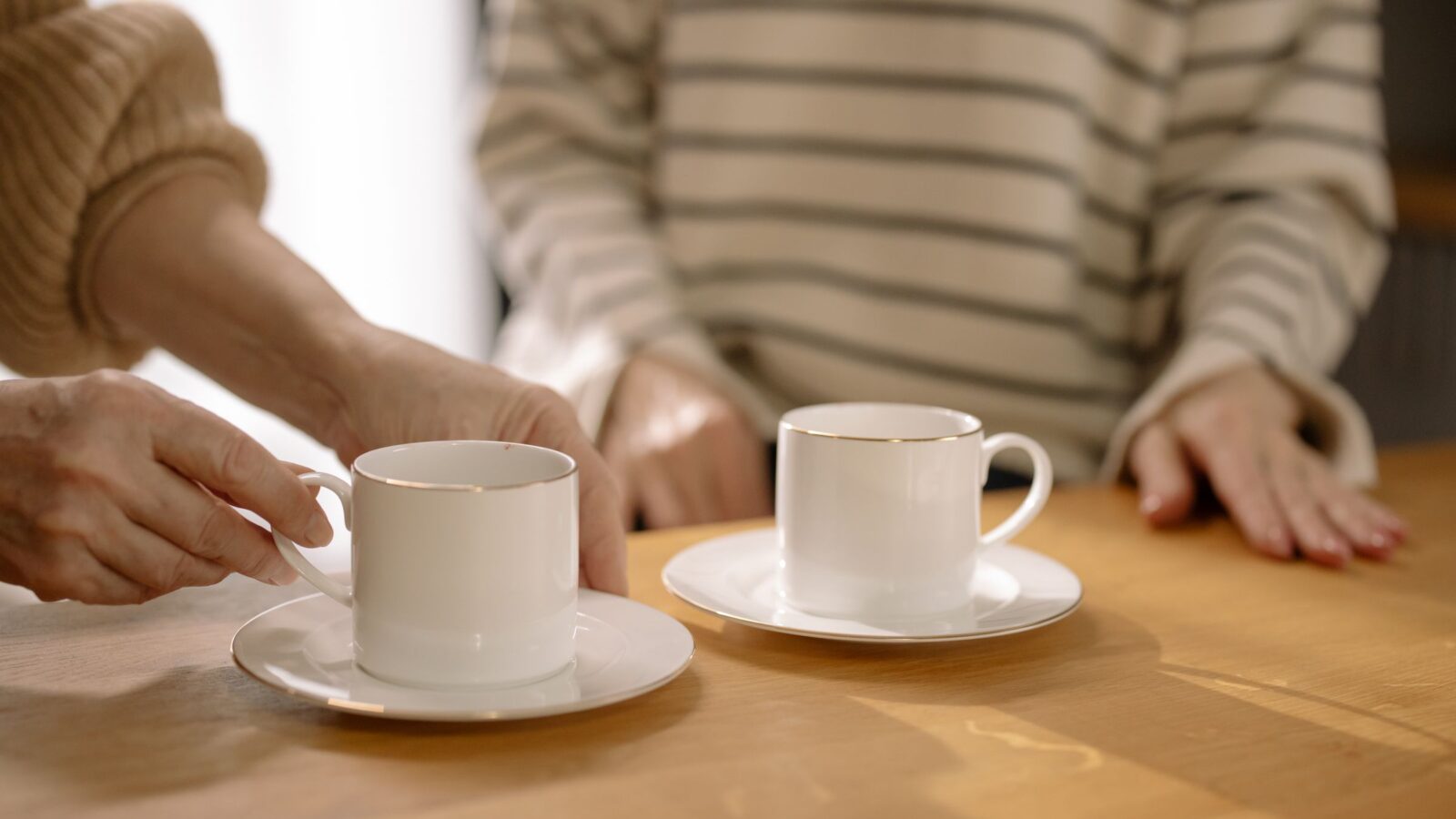 Two people at a kitchen table with cups of tea