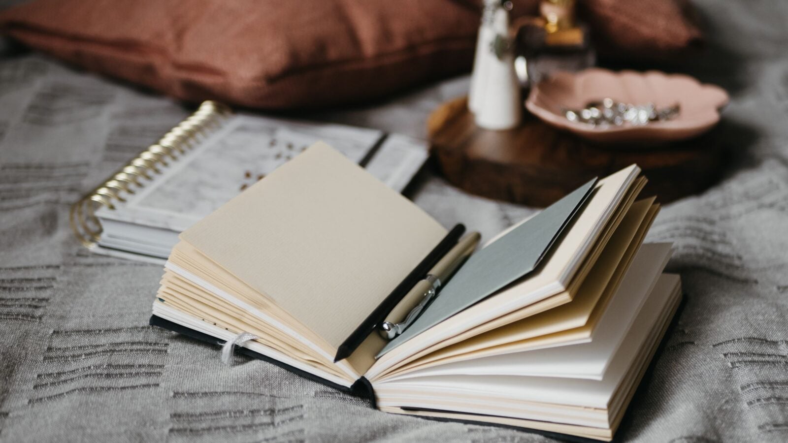 Open notebooks and a pen resting on a soft blanket